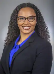 Ginger Research and Production Team Professional woman in business attire with glasses, smiling confidently.